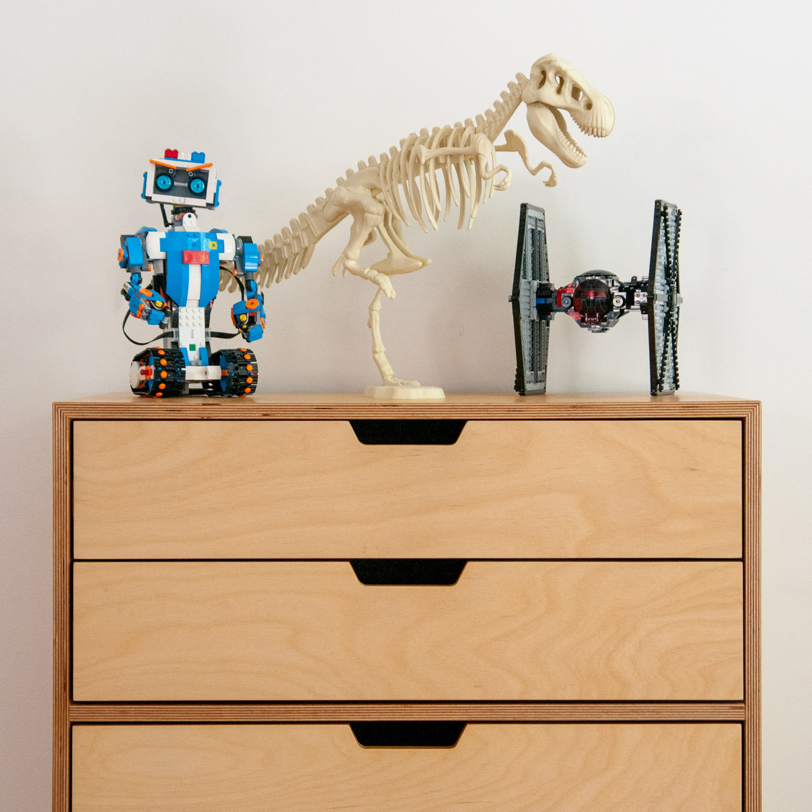 Dresser front view with Lego Tie Fighter, Lego robot, and T-rex model skeleton on top