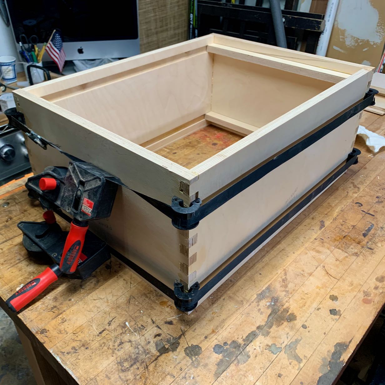 Build process photo showing a cabinet with finger joints, glued together and clamped